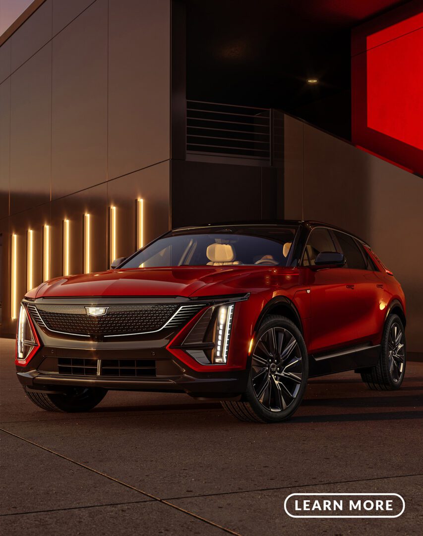 A red cadillac xt5 suv parked in front of a building at night.