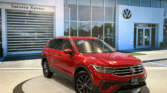 A red volkswagen tiguan in front of a dealership.