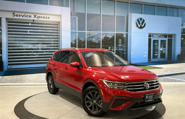 A red volkswagen tiguan in front of a dealership.